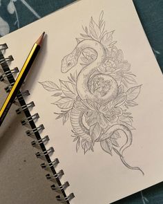 a drawing of a snake and flowers on a piece of paper with a pencil next to it