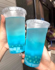 two people holding up blue drinks in their hands