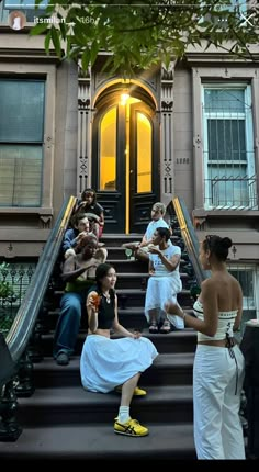 several people sitting on the steps of a building with one woman in a white dress