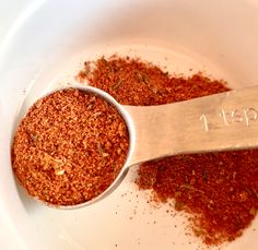 a white bowl filled with spices next to a measuring spoon