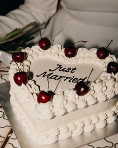 a heart shaped cake with cherries on it and the words just married written on top