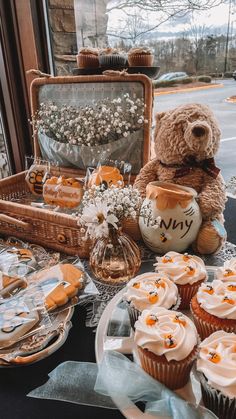 a teddy bear sitting on top of a table next to cupcakes