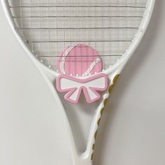 a pink and white tennis racquet with an ornament on the back