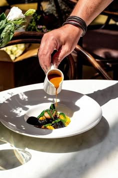 a person pouring sauce on a plate with food