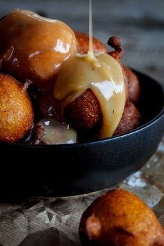 a bowl filled with donuts covered in caramel sauce and drizzled with icing