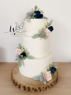 a three tiered white wedding cake with blue and pink flowers