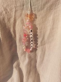 a white shirt with beads and charms hanging from it's back end on a string