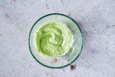 a bowl filled with green cream on top of a table