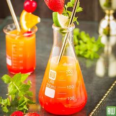 a pitcher filled with liquid and strawberries on top of a table next to another jug