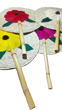 three paper plates with flowers on them and two wooden sticks sticking out of the top