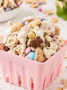 a pink plastic container filled with cereal and candy mix on top of a white table