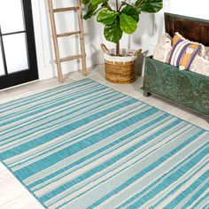 a blue and white striped rug in a living room with a potted plant on the floor