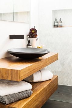 a bathroom with a sink, mirror and towels on the shelf in front of it