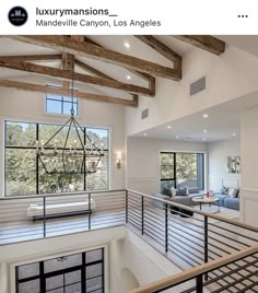 an open floor plan with wood beams and glass railings in the living room area