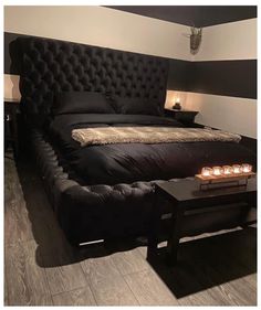 a black bed with candles on it in a room that has striped walls and wood floors