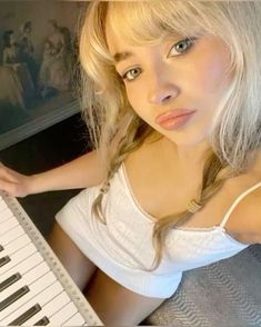 a woman with blonde hair sitting next to a piano