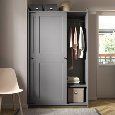 an open gray closet with clothes hanging on the door and two white chairs next to it