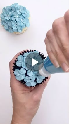 a person is holding a cupcake with blue frosting