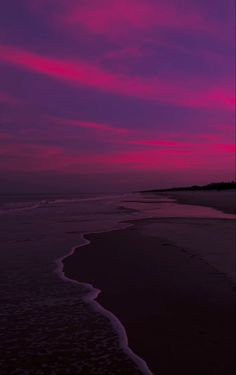 the sky is pink and purple as it sets over the water at sunset on an empty beach