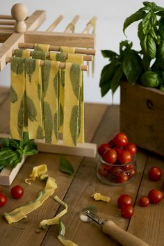 tomatoes, basil, and other vegetables are on the table next to some pasta cutters