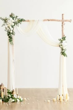 a white wedding arch decorated with flowers and candles