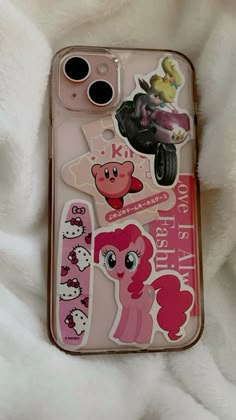 an iphone case with pink pony stickers on the front and back cover, sitting on top of a white blanket