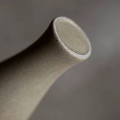 a white vase sitting on top of a table next to a gray wall and floor