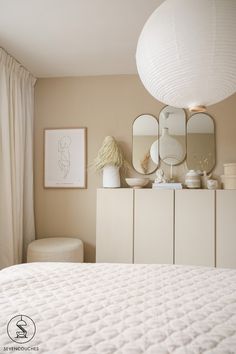 a white bed sitting next to a dresser with mirrors on it's top shelf