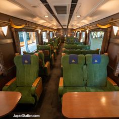 an empty train car with green seats and wooden tables