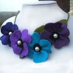 a close up of a necklace on a mannequin with flowers and pearls hanging from it