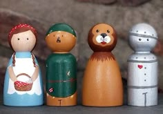 five wooden dolls are standing next to each other in front of a stone wall,