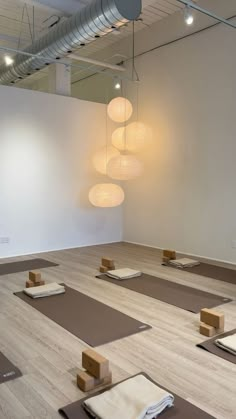 an empty room with yoga mats on the floor and lights hanging from the ceiling above