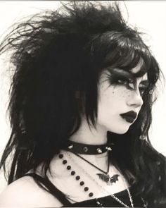 a black and white photo of a woman with long hair wearing choker necklaces