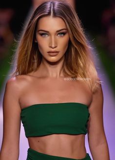 a model walks down the runway in a green dress