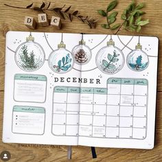 an open planner with christmas ornaments and greenery on the pages, next to a wooden table