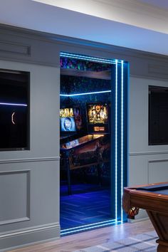 a pool table and some televisions in a room with blue lights on the walls