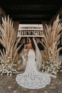 a woman in a wedding dress standing next to some tall grass and pamylions