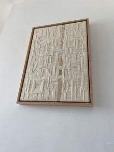 a white wall with a wooden frame on top of it that has an abstract pattern