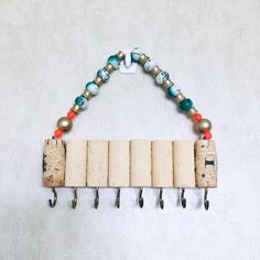 a cork and metal wall mounted coat rack with beads hanging from it's sides