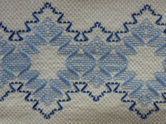 an embroidered design on fabric with blue stitching in the center and two rows of stitches at the bottom