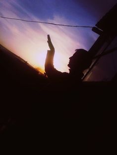 the silhouette of a person raising their hand in the air