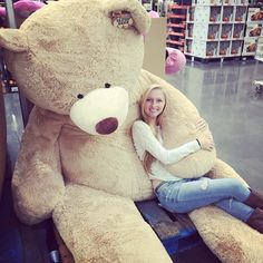 a woman sitting on top of a giant teddy bear