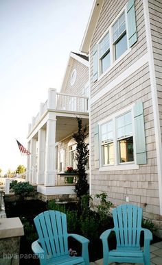 two blue chairs sitting in front of a house