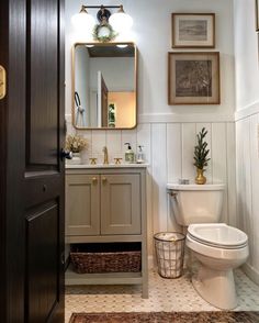 a white toilet sitting next to a sink in a bathroom under a mirror and lights