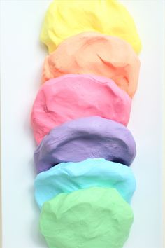 there are five different colored ice creams in the same row and one is pink, blue, green, yellow, purple, and orange