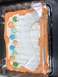 a cake in the shape of a shoe with white icing and colorful buttons on it