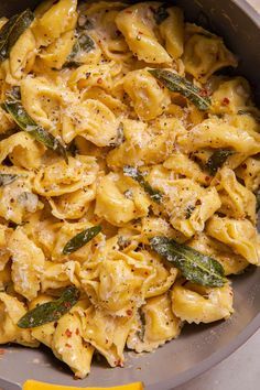 a pan filled with pasta and spinach on top of a table