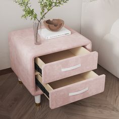 a pink end table with two drawers and a plant in a glass vase on top