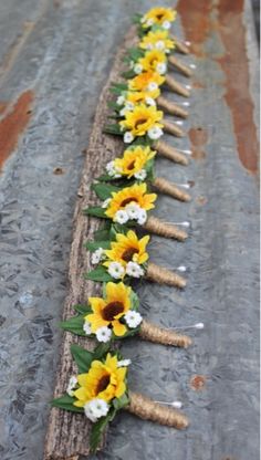 a long row of sunflowers and grass sticks with white flowers on them sitting on the ground