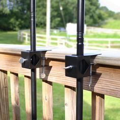 two black metal poles are on the outside of a wooden deck with grass and trees in the background